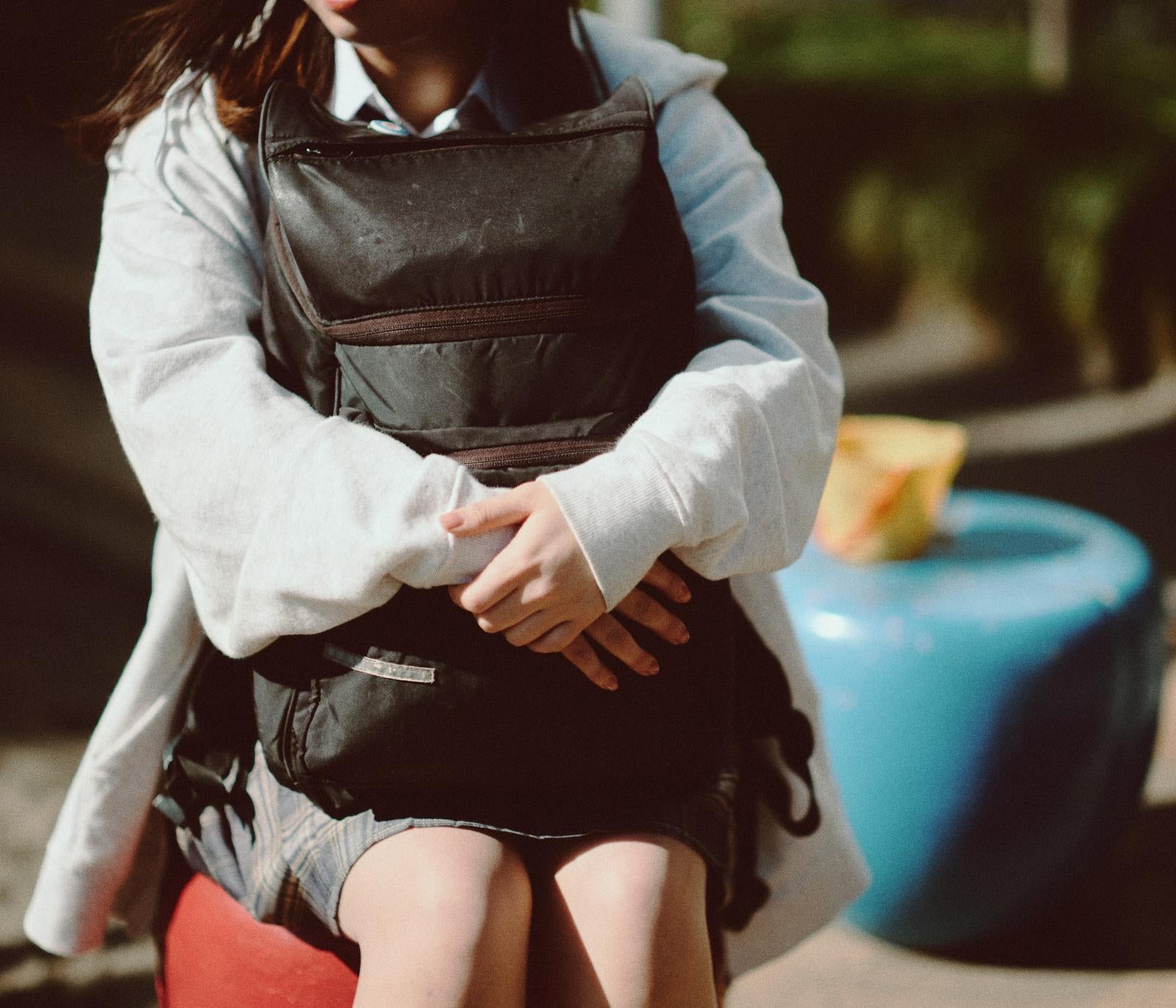 「大きなリュックを抱きしめてひとやすみする女子高生」の写真