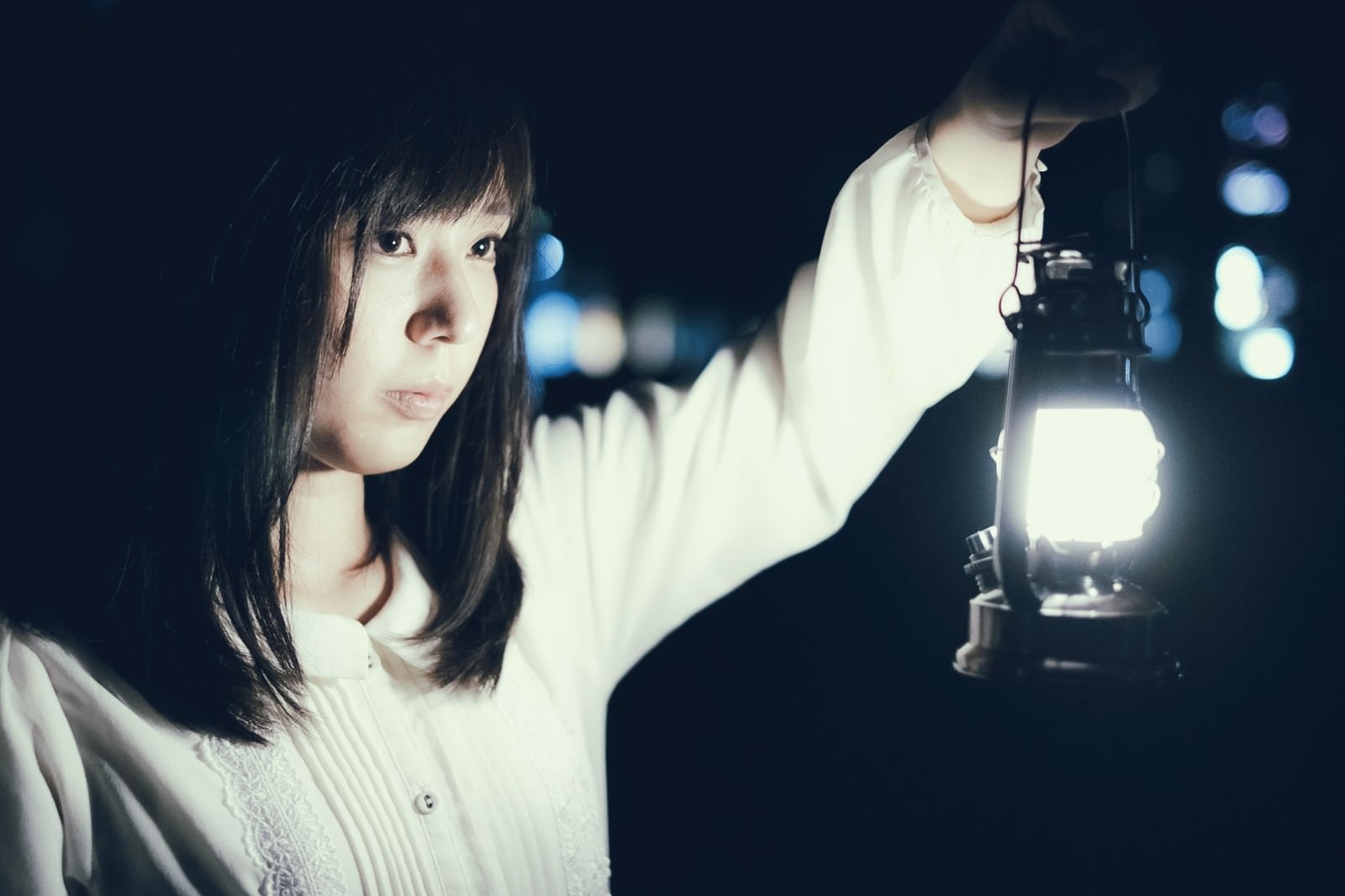 「夜に明かりを灯すランタンと女性」の写真［モデル：さとうゆい］