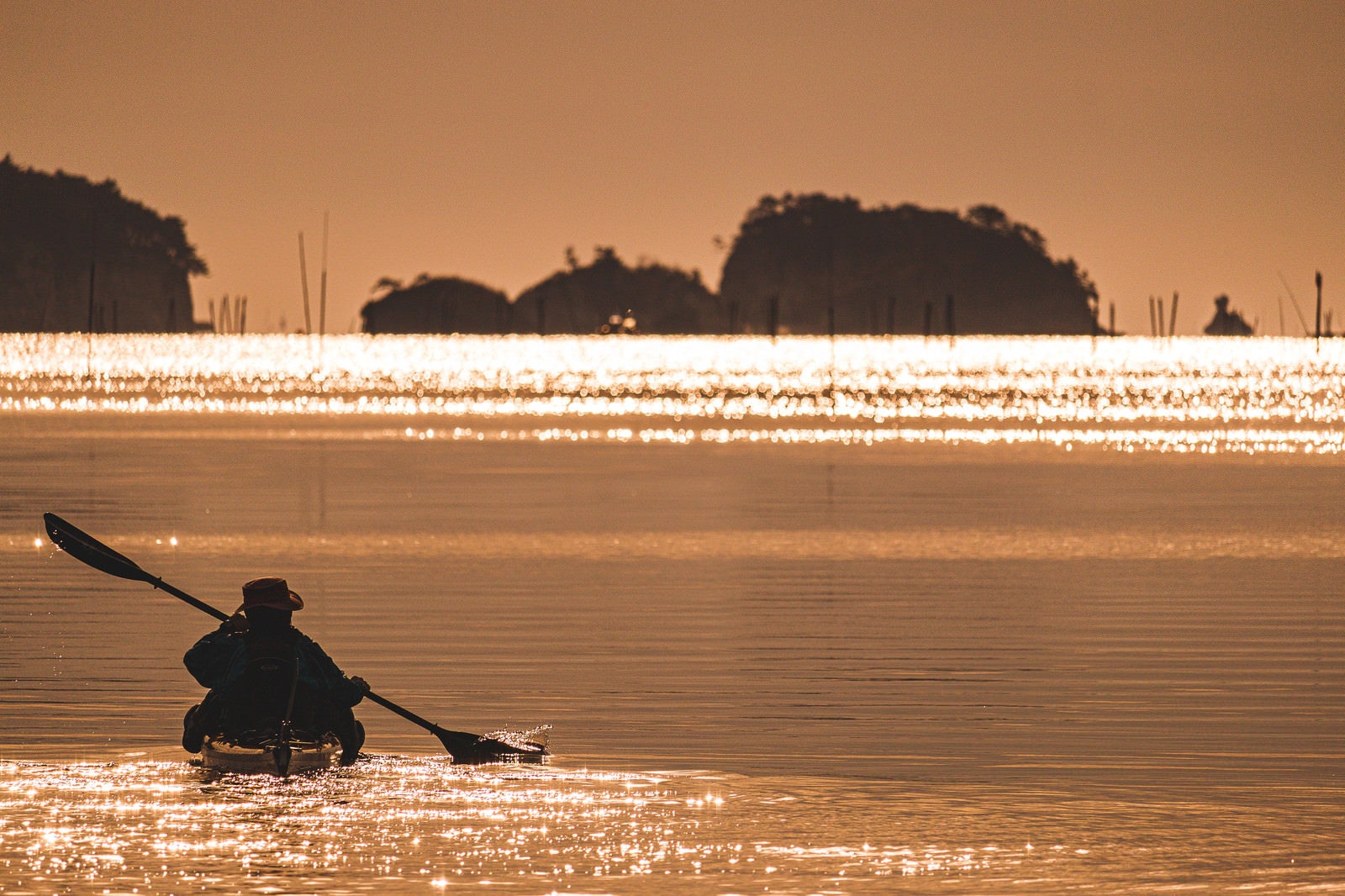 「朝日の中を漕ぎ出すカヌーのシルエット」の写真