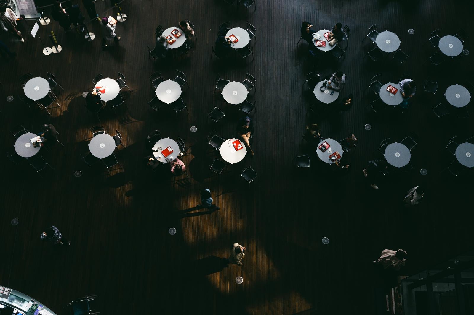 「並ぶ丸テーブルと休息する人ら」の写真