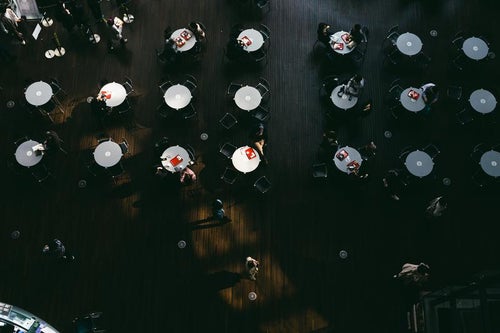並ぶ丸テーブルと休息する人らの写真