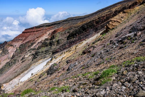 重なり合う地層が見える旭岳の爆裂火口の写真