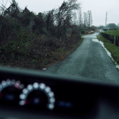 雨の中の農道を走る車から見た景色の写真