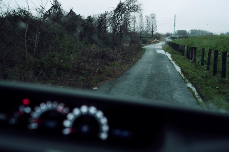 雨の中の農道を走る車から見た景色の写真