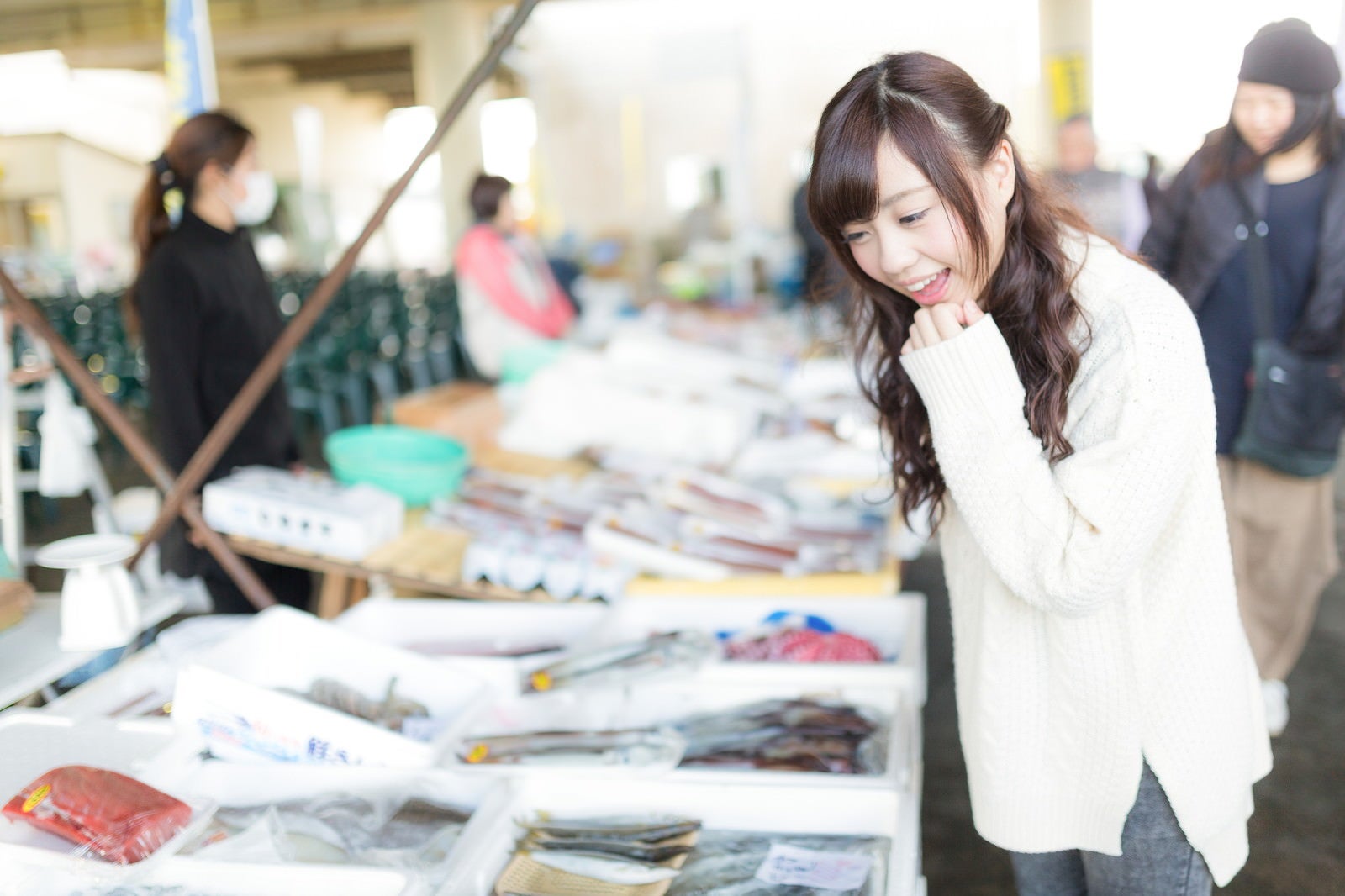 「朝市の新鮮な魚を見て回る女性」の写真［モデル：河村友歌］