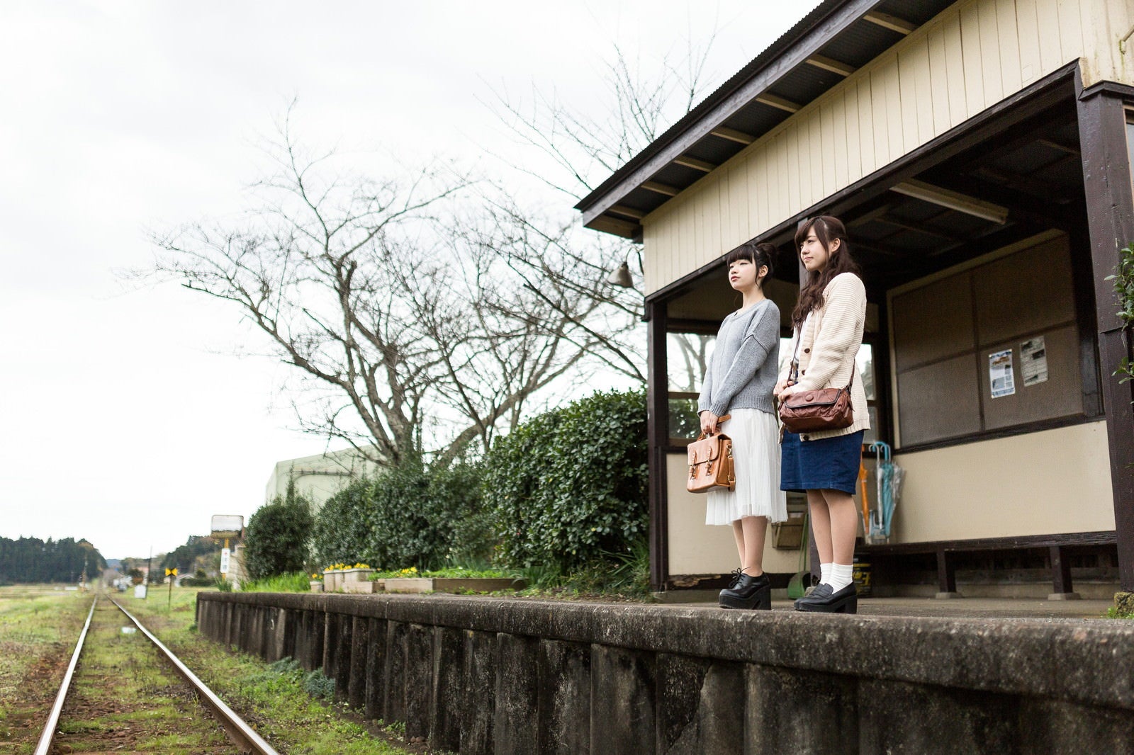 「無人駅で電車を待つ女性」の写真［モデル：河村友歌 渡辺友美子］