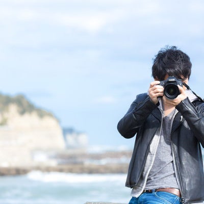 海岸でカメラを構える男性の写真