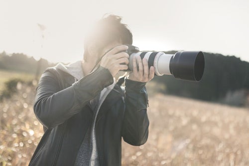 望遠レンズで風景を撮影するカメラマンの写真