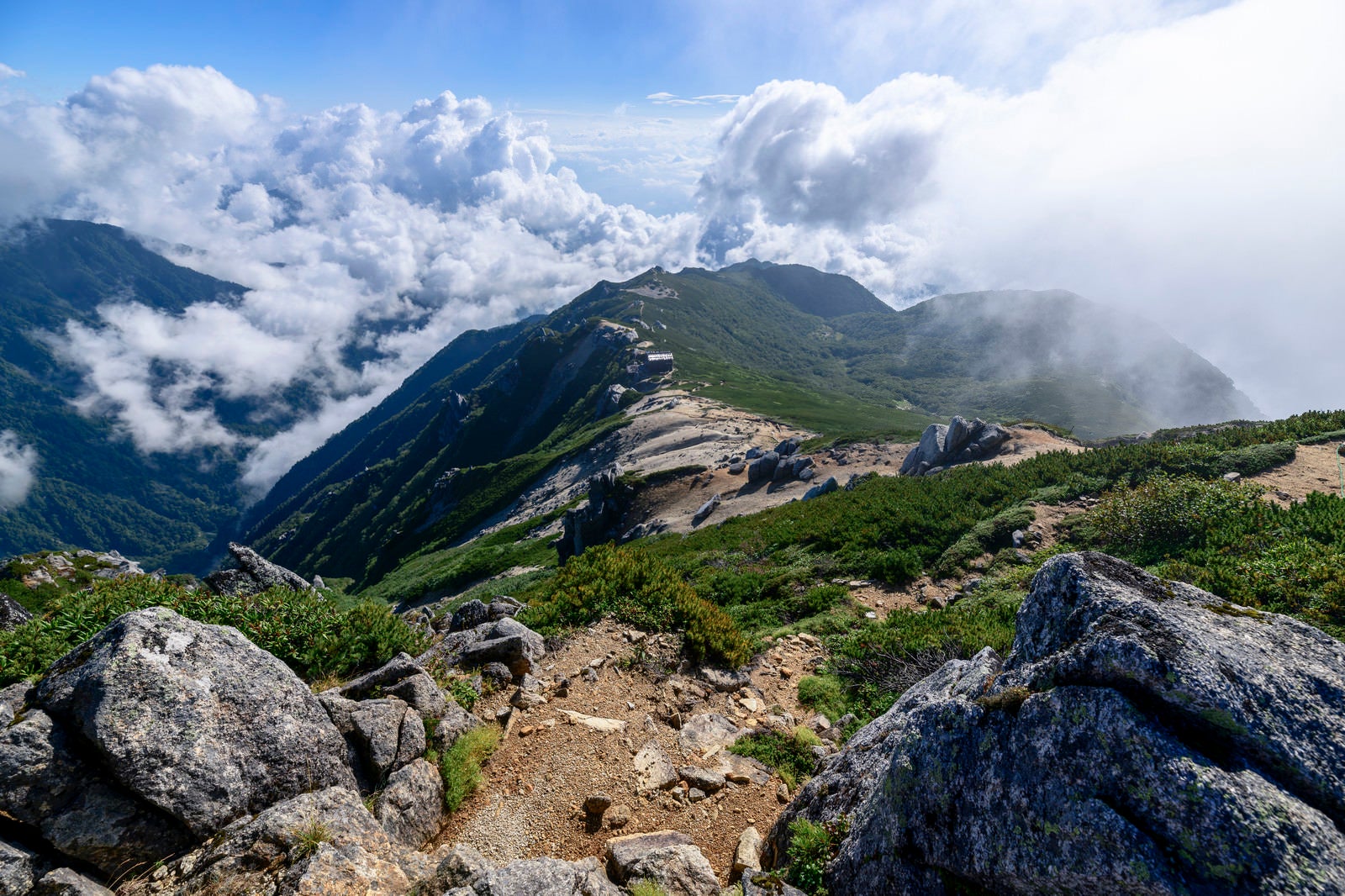 「巨大な雲が迫りくる駒峰ヒュッテと稜線」の写真
