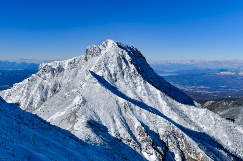 快晴の空の元雪化粧した阿弥陀岳（あみだだけ）の写真