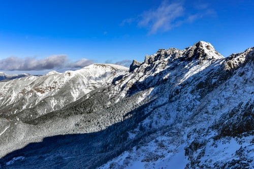 朝日に照らされる雪の横岳（よこだけ）と硫黄岳（いおうだけ）の写真