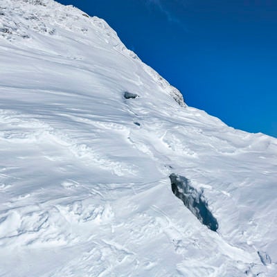 今にも裂けて落ちそうな谷川岳の雪庇の写真