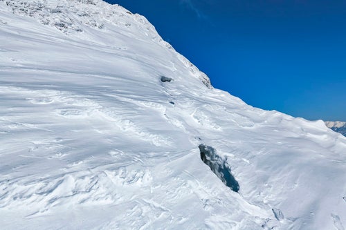 今にも裂けて落ちそうな谷川岳の雪庇の写真