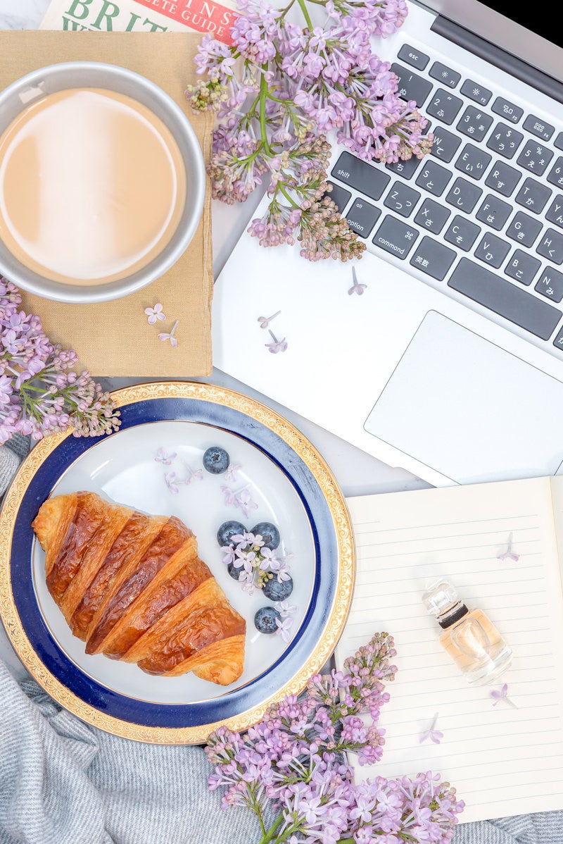 「ノートパソコンのキーボードと朝食のクロワッサン」の写真
