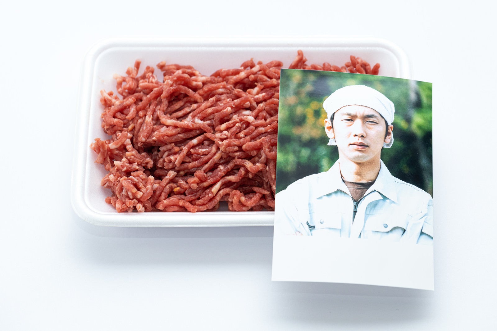 「ミンチ肉の食肉トレーと生産者さんの顔写真」の写真［モデル：大川竜弥］
