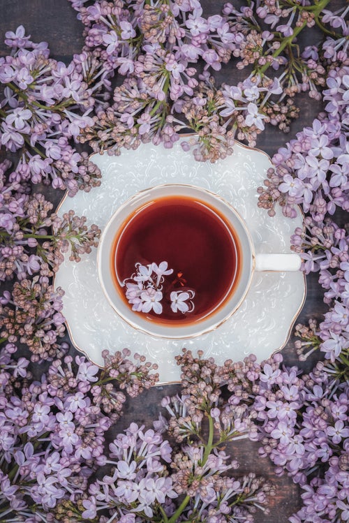 紅茶に浮かぶライラックの花びらの写真