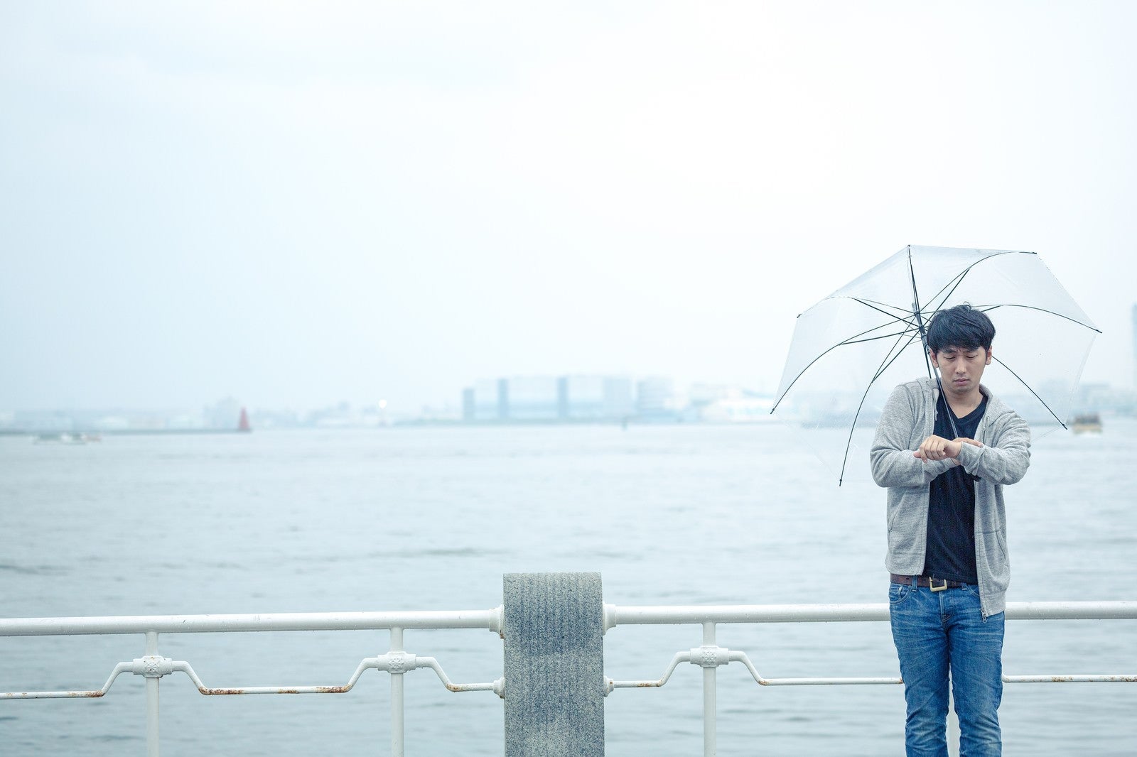「雨の日の初デート、時間を確認するしぐさで高鳴りをごまかす男性」の写真［モデル：大川竜弥］
