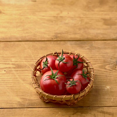 籠に入った蔕付きミニトマトの写真
