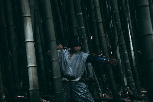 薄暗い竹林の中から大弓を構える野盗の写真