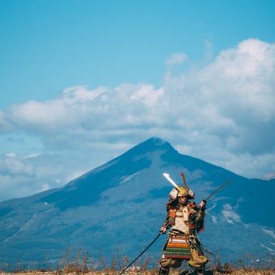 磐梯山を背に二刀流をキメる大鎧武士の写真