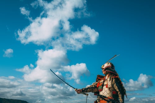日本刀を空に構える大鎧を纏う武士の写真
