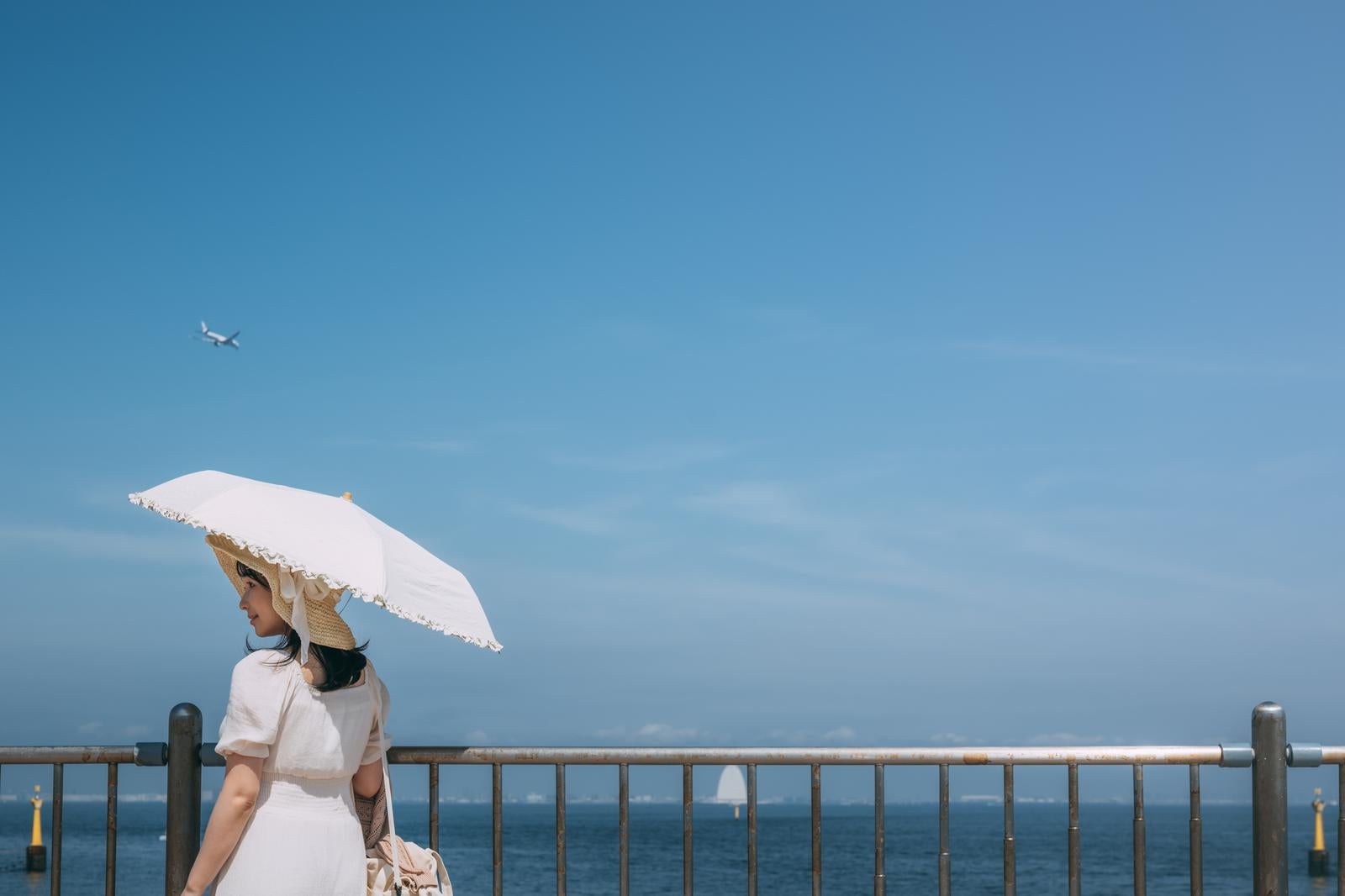 「海ほたるの西展望デッキと日傘をさす女性」の写真［モデル：茜さや］