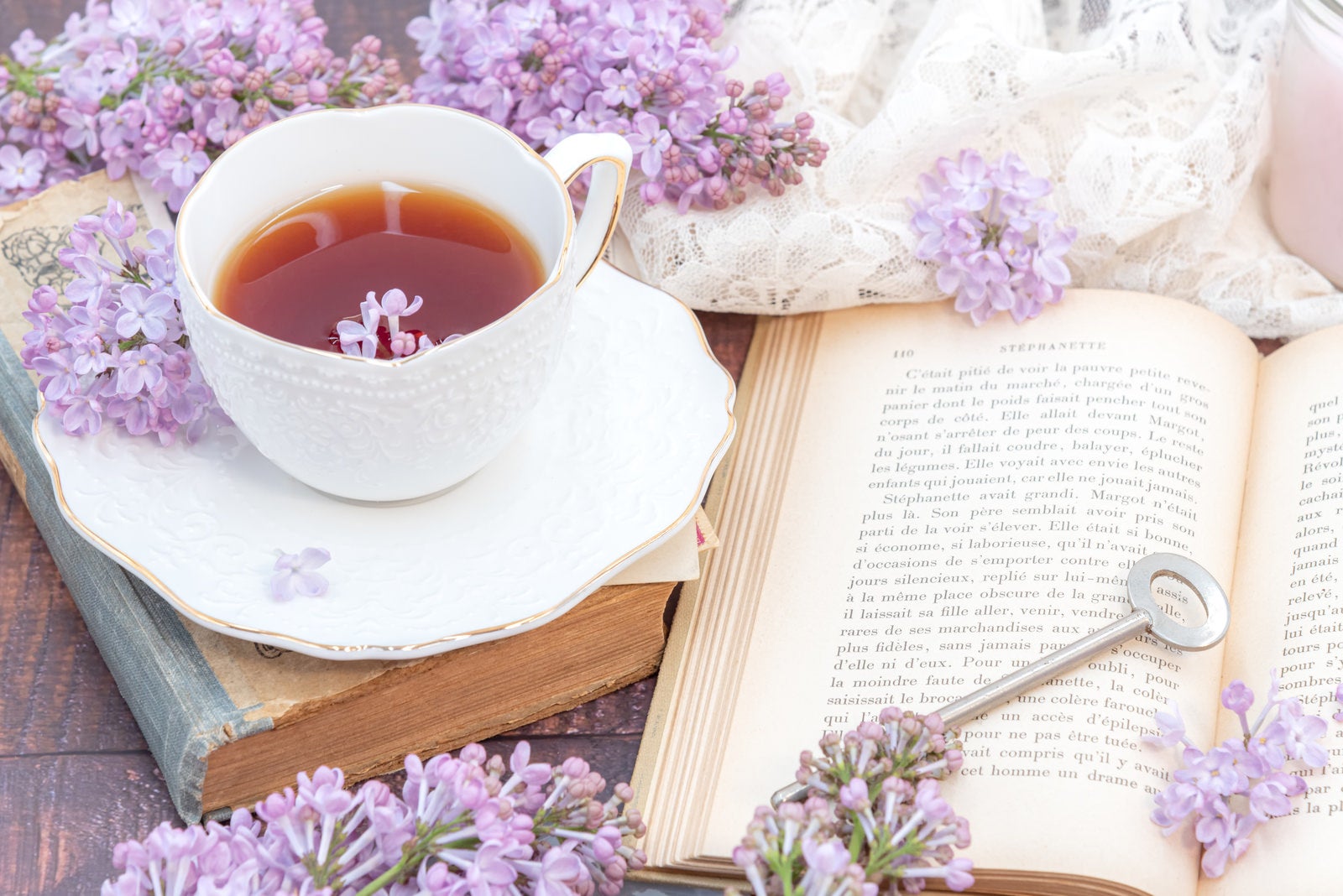 「無造作に置かれた鍵とライラックの花びら浮かぶ紅茶」の写真