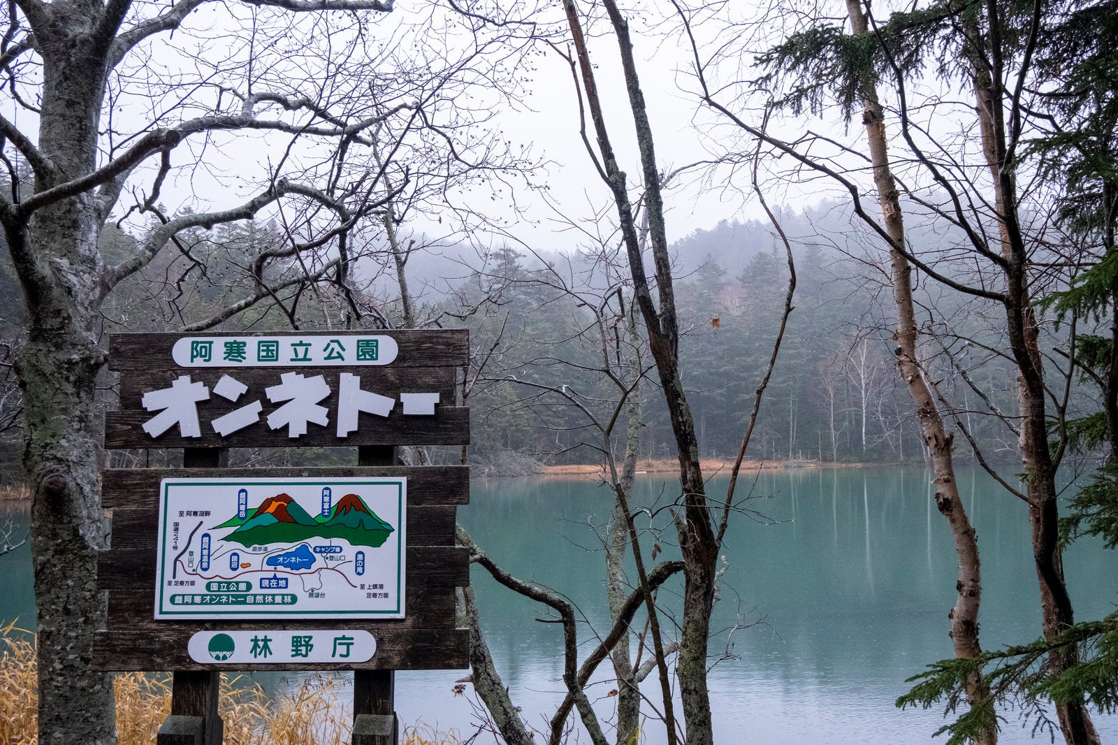 北海道阿寒国立公園オンネトーの湖畔に設置された木製案内看板と冬景色の湖