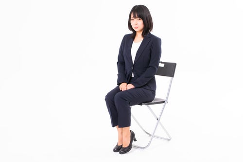 椅子に座る受付の女性会社員の写真