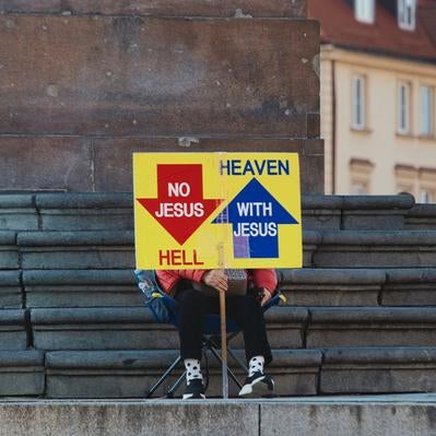 ワルシャワの石段に座りメッセージ性の強い看板を掲げる人物の写真