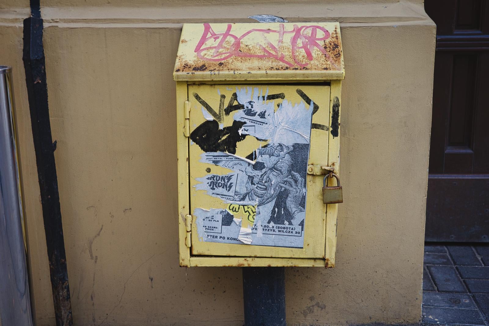 黄色い配電盤に落書きとステッカーが貼られた写真