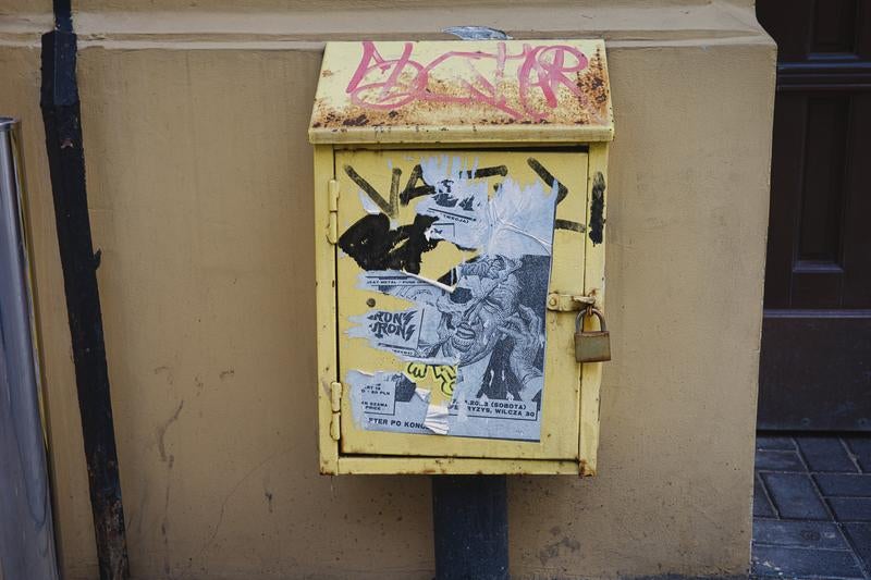 街角に残る黄色い配電盤と落書きされたステッカー