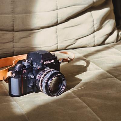 柔らかな光に包まれるNikon F3フィルムカメラとオレンジのストラップの写真