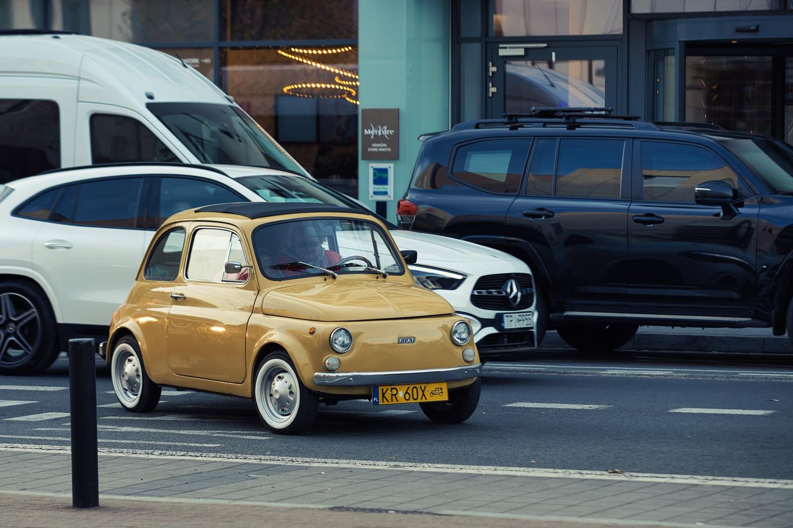 A classic yellow Fiat 500 speeding through the city streets - free stock photo