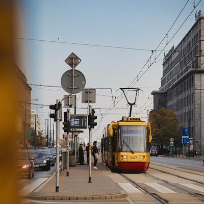 黄色い路面電車が停留所に着く都会のストリートスナップ（クラクフ）の写真
