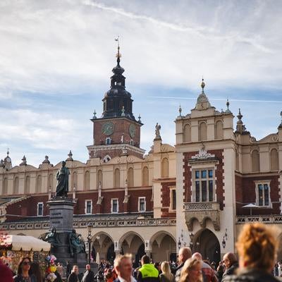 中世ヨーロッパの面影を残すクラクフ織物会館と時計塔、市民の憩いの広場の写真