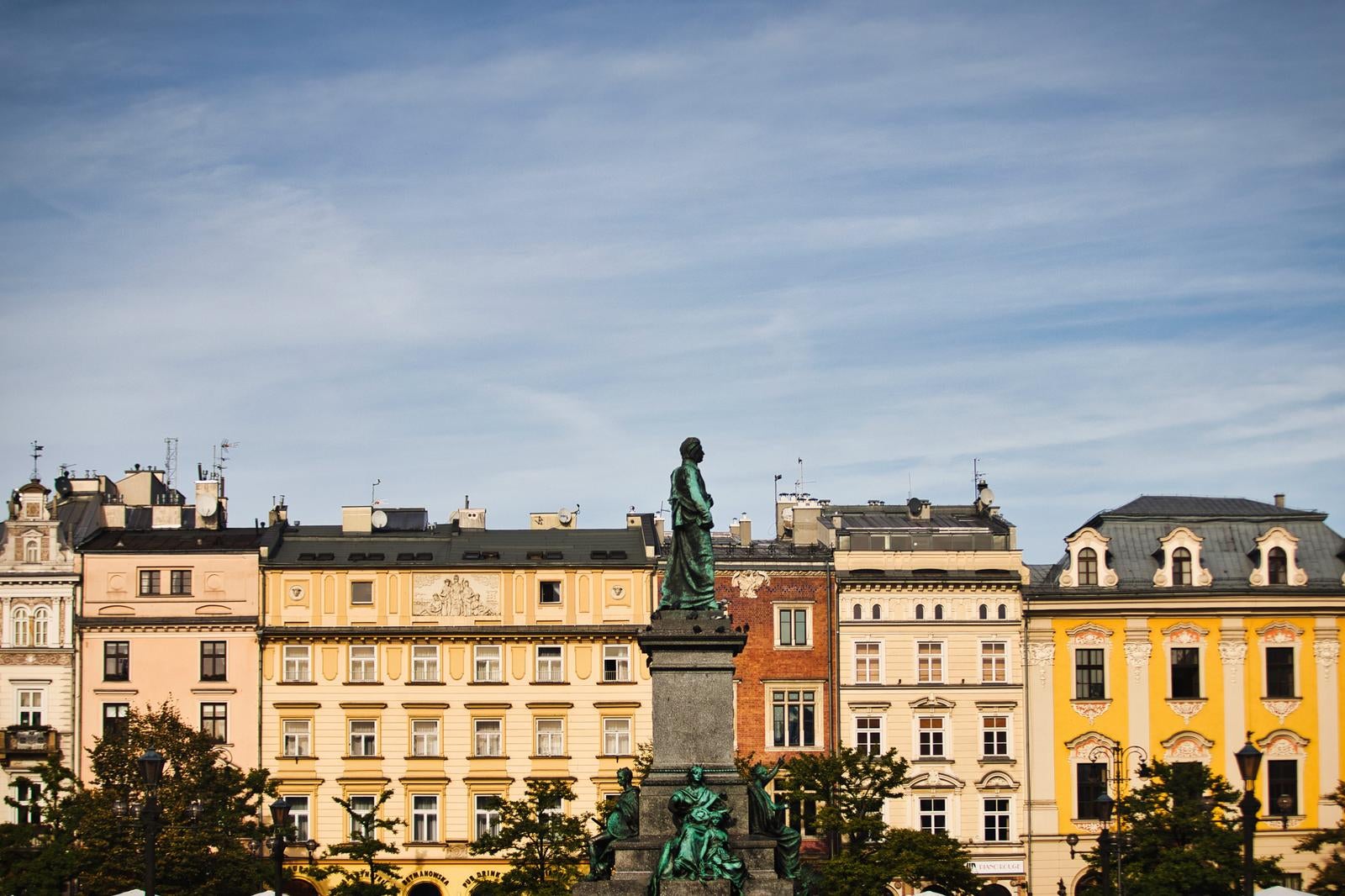 クラクフ中央市場広場の銅像と色とりどりのファサード建物