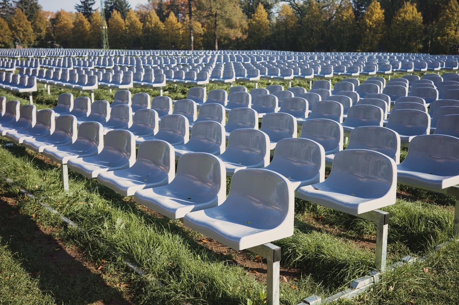 ポーランドのチェンストホバの芝生に整然と並べられた無数の白い椅子と黄色く色づいた森