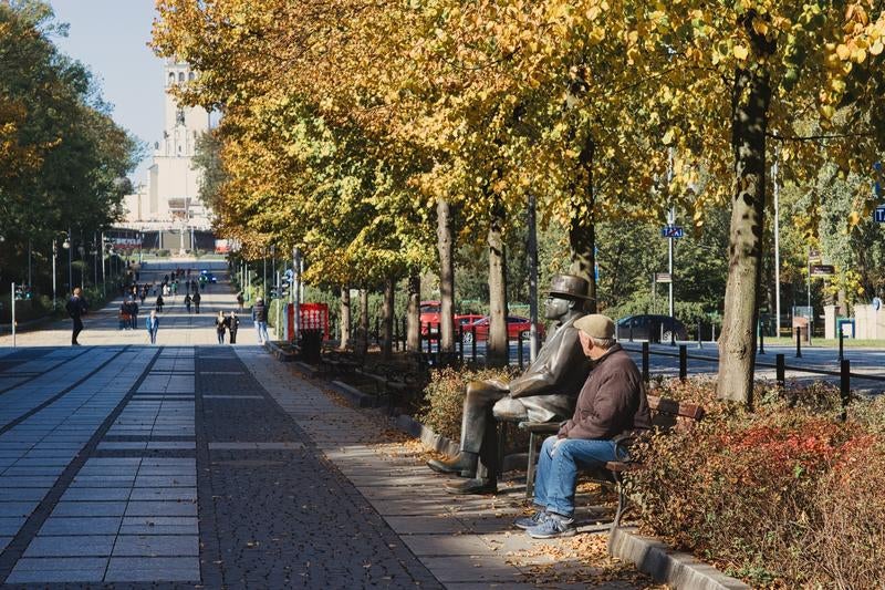 チェンストホバの秋色に染まる並木道でベンチに座る男性