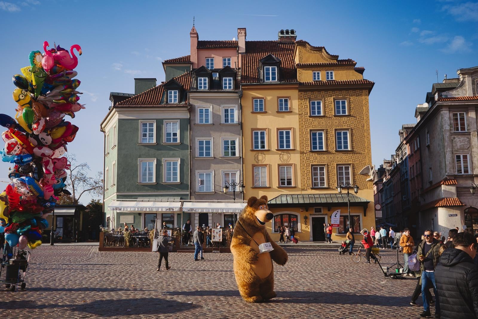 石畳の広場でバルーンとクマの着ぐるみが観光客を楽しませるワルシャワ旧市街