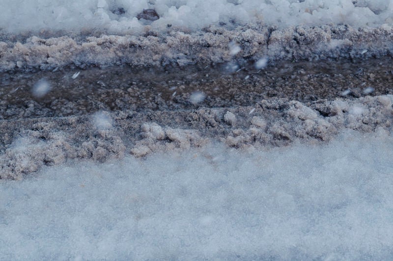 新雪と圧雪が層をなす雪道にくっきり残るタイヤ痕の写真