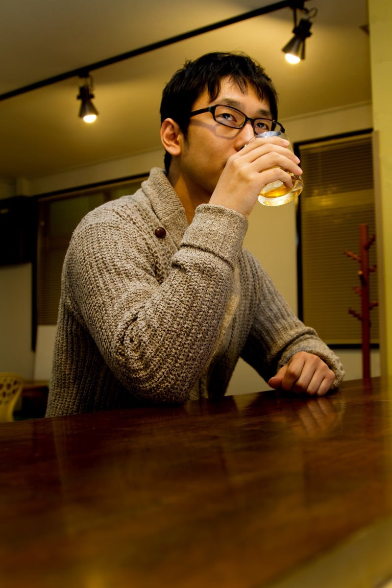 「バーでグラスを持つデザイナー」の写真［モデル：大川竜弥］