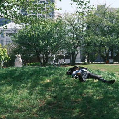 昼下がりに公園で寝るサラリーマンの写真