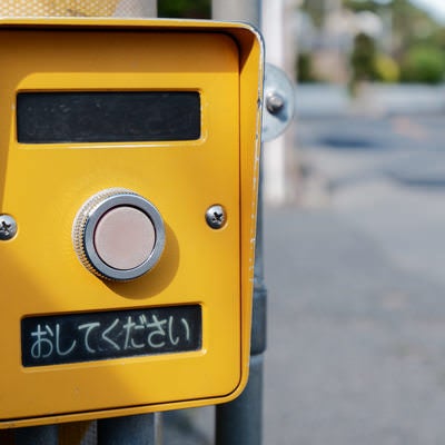 黄色い押しボタン式信号の「おしてください」ボタンの写真