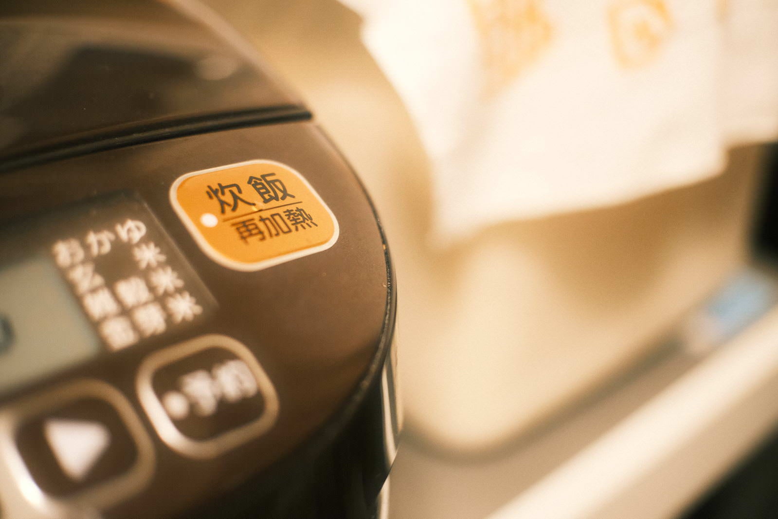 オレンジ色に光る電子ジャーの炊飯ボタンと操作パネル