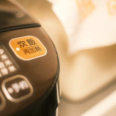 オレンジ色に光る電子ジャーの炊飯ボタンのアップの写真