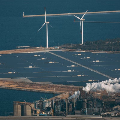 海岸沿いの風力発電設備と太陽光パネルの写真