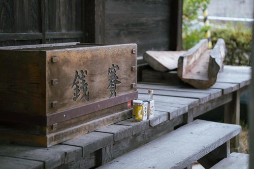 岳温泉の賽銭箱前に置かれた酒の写真