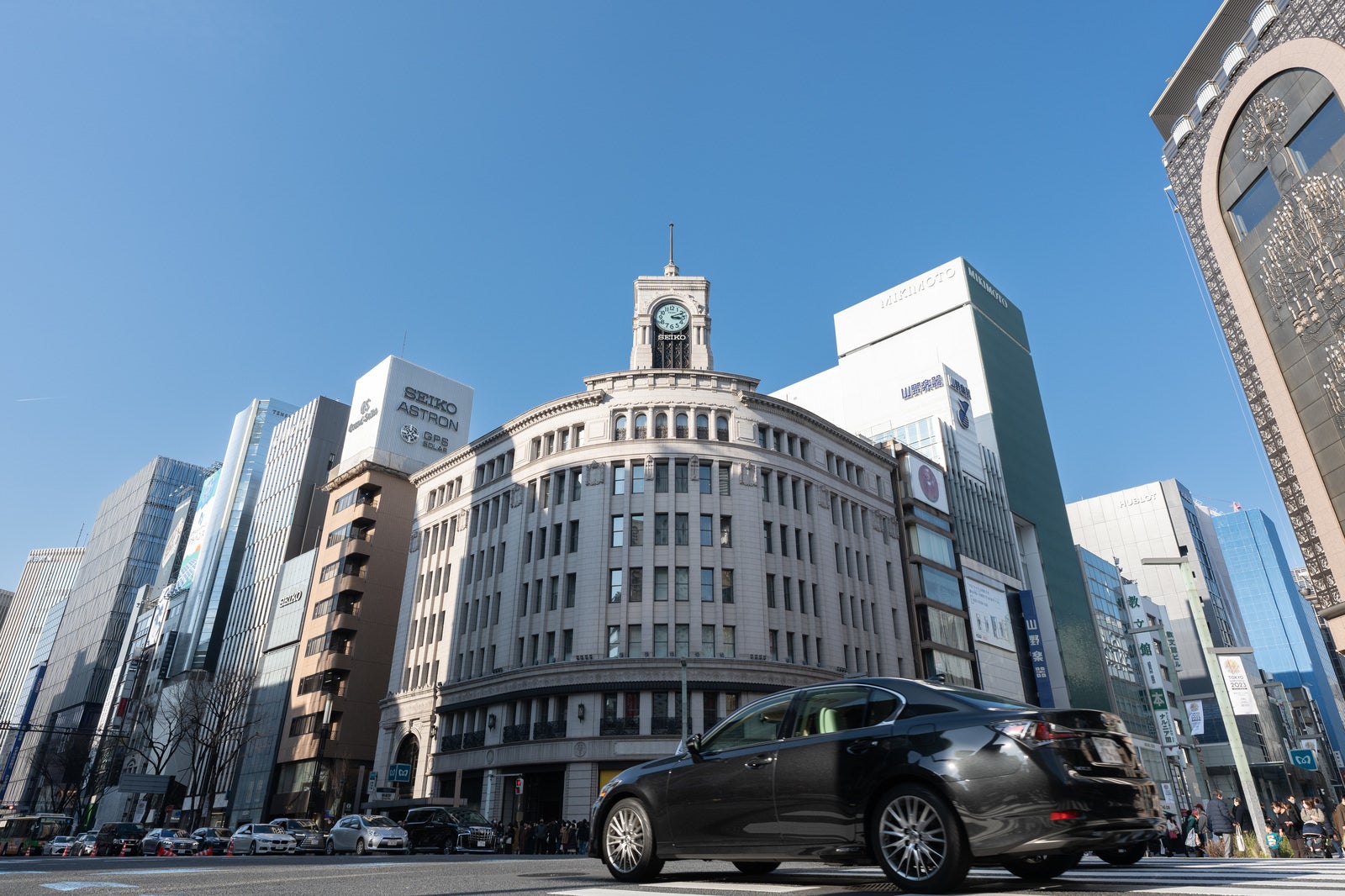 「銀座和光の時計台と車が往来する交差点」の写真