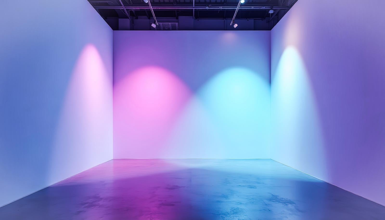 Gallery space with three-color lighting projected onto white concrete floor